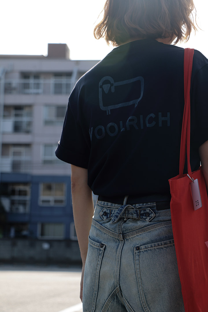 バックプリントのウールリッチのTシャツを着用する女性