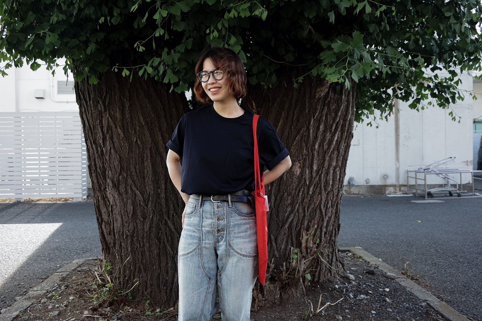 木の前でウールリッチのTシャツを着用する女性